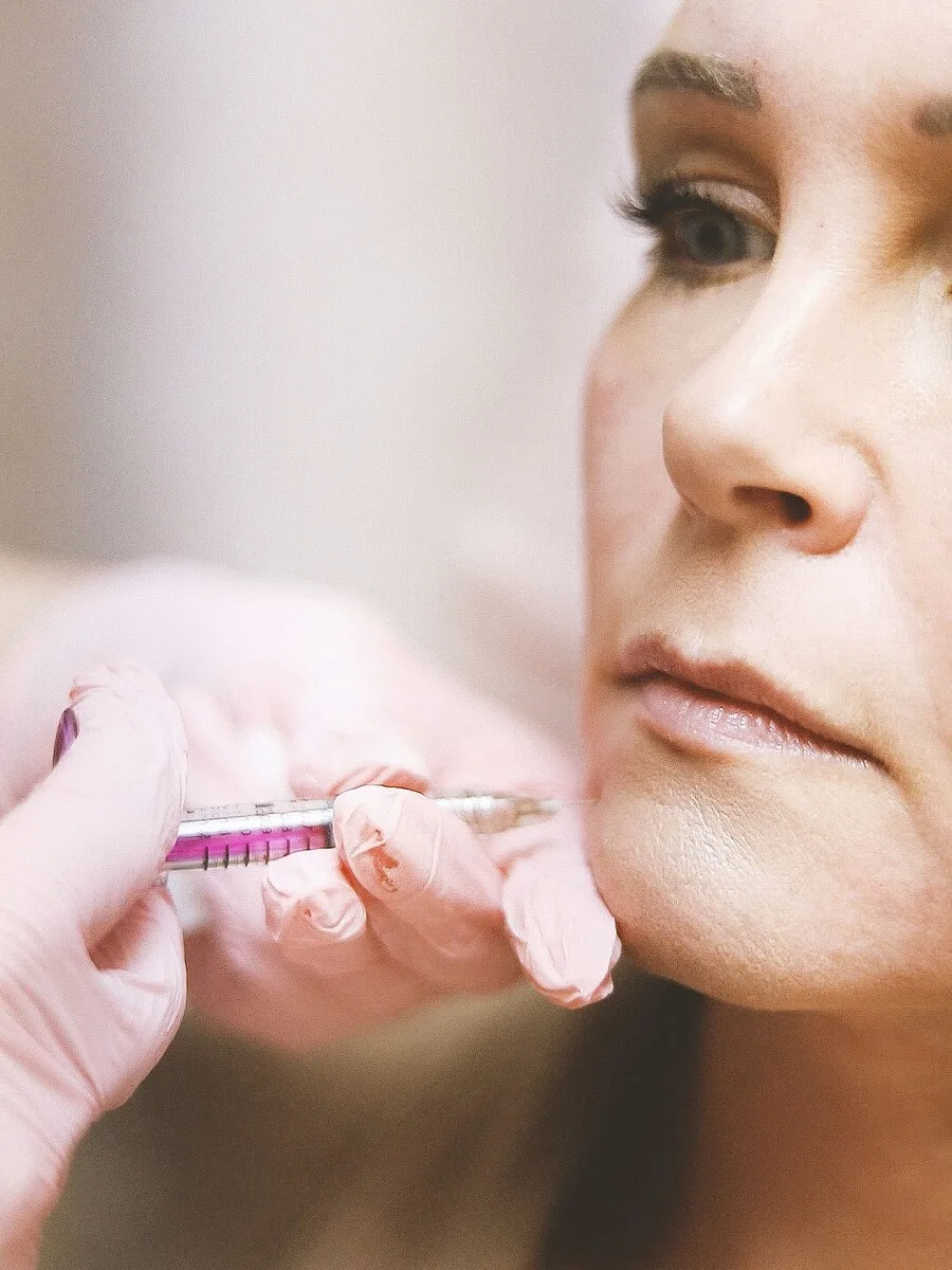 A nurse injector administering a dermal filler treatment to a client’s lip